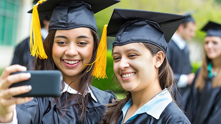 Candid photo of two students taking a selfie at graduation